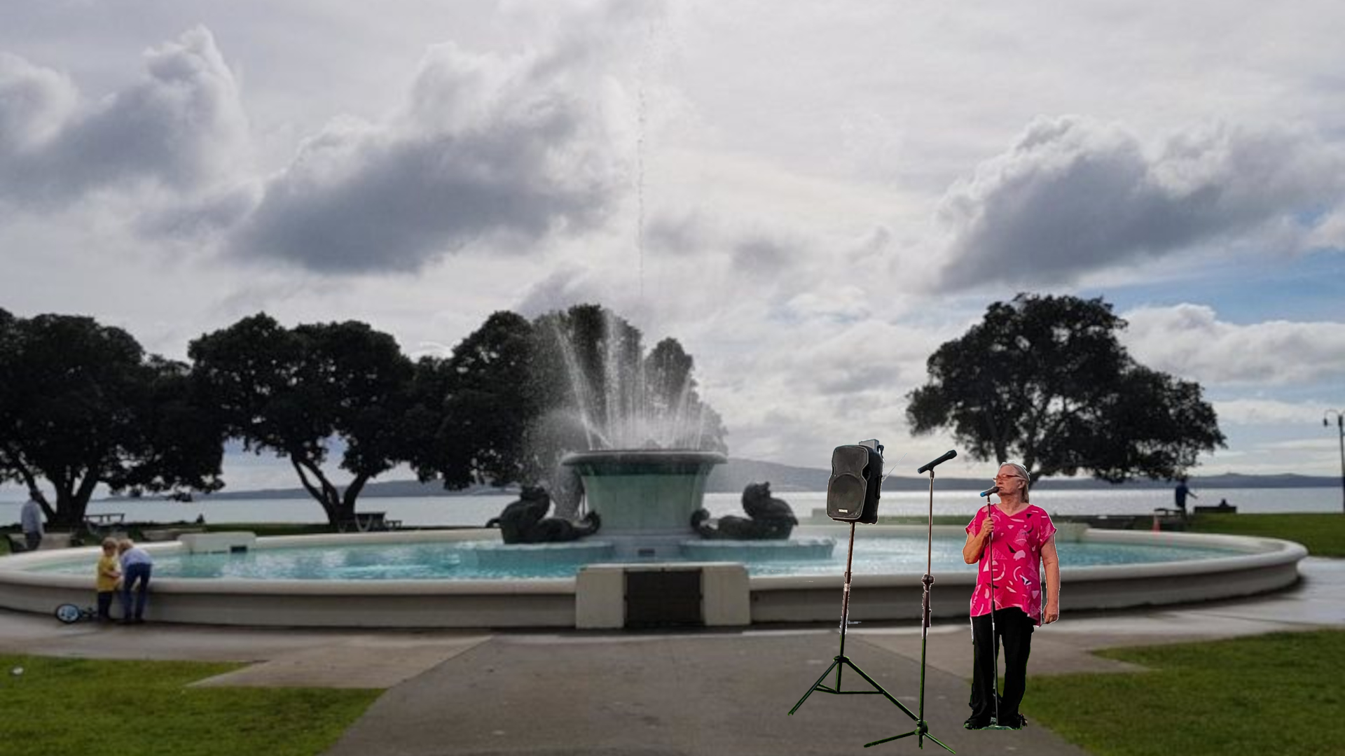 A comedian stands in front of a fountain with a microphone